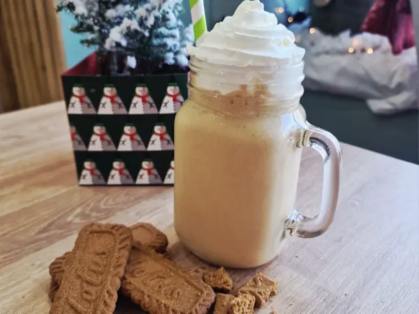 Biscoff milkshake topped with whipped cream in a mason jar, served with Lotus biscuits at Cristina's Cafe Romford